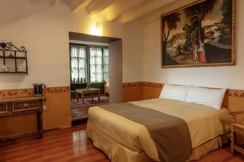 库斯科坦博德尔阿列罗精品酒店的卧室配有一张床,墙上挂有绘画作品