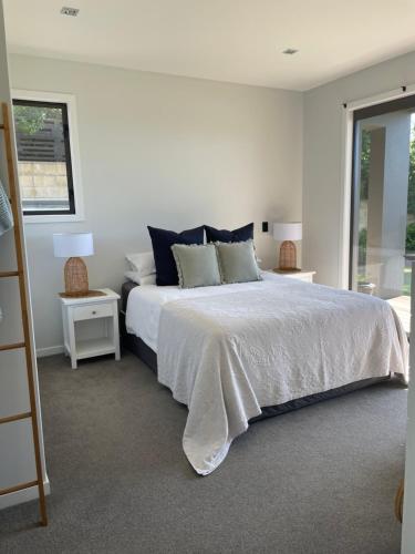 基督城Luxury 2 Bdrm Apt w Private Pool located on Scarborough Hill, Sumner. Christchurch的一间白色卧室,配有床和2个床头柜