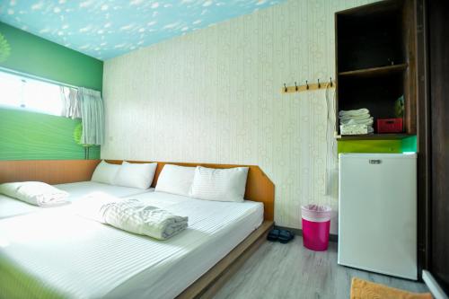 小琉球岛野原星之宿的一间小卧室,配有一张带白色床单的床和一台冰箱