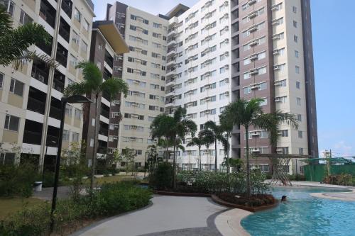伊洛伊洛Avida Atria Tower I Cozy Condo Great Location的公寓大楼设有游泳池和棕榈树