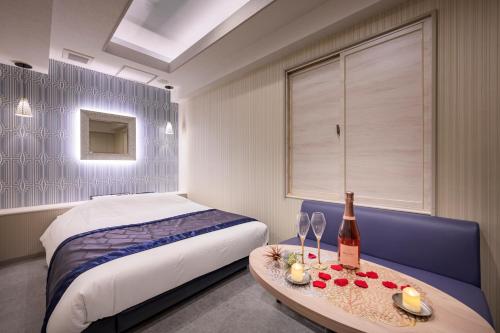 东京Hotel Plantan - Adult Only的一间卧室配有一张床和一张桌子及一瓶葡萄酒