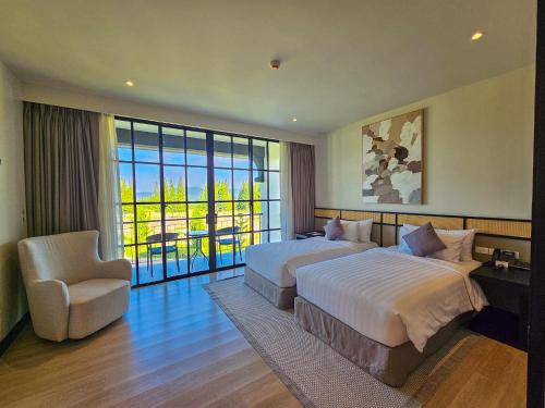 Khao YaiBergh Apton Khao Yai的大型酒店客房,配有两张床和椅子