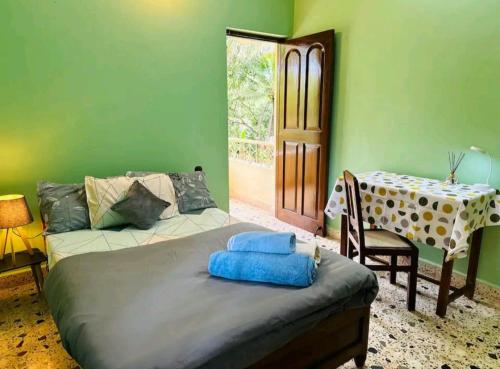 马焦茹达La Des Chateau Holiday Suites的一间卧室设有绿色的墙壁、一张床和一张桌子