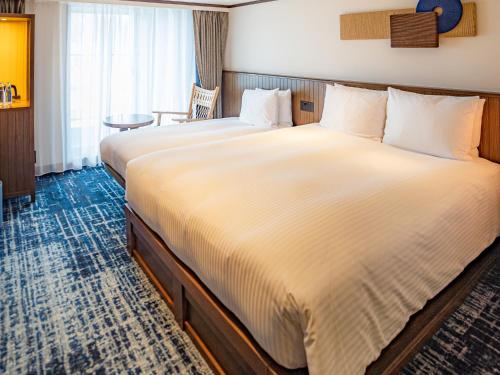 高山Mercure Hida Takayama的酒店客房设有两张床和一张桌子。