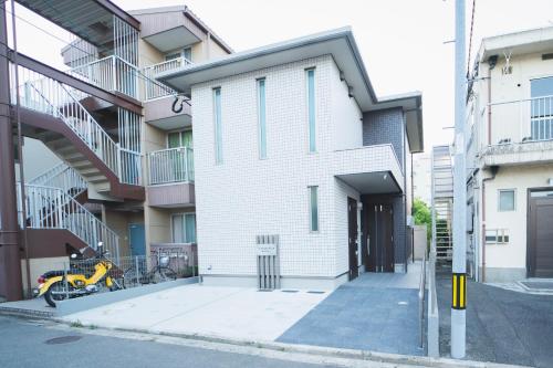 福冈Vieuno Stay Hakata 1的一座白色的建筑,前面有一辆自行车停放