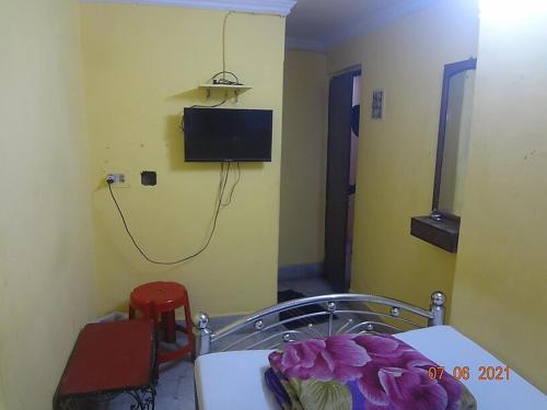 加尔各答Khaja Hotel的一间设有桌子和墙上电视的房间