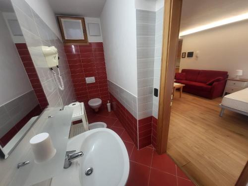 平佐洛monolocale Ambrosi的一间带水槽的浴室和一张红色沙发