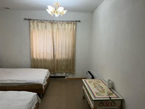 乌兰巴托加纳旅馆的一间卧室设有两张床和一个带吊灯的窗户。