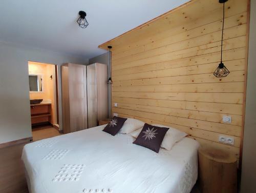 蒂涅Luxueux appartement T4 skis aux pieds à Tignes le Lac的卧室配有白色的床和木墙