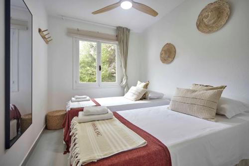 比尼贝卡OasisBlanc Binibeca的白色客房的两张床,设有窗户