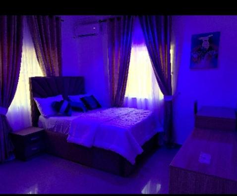 Specfield Court And Apartment Sun City的紫色卧室设有一张床和一个窗户