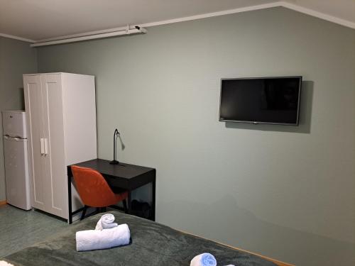 萨普斯堡Tune Hotell Sarpsborg的客房设有一张床、一张书桌和一台墙上的电视