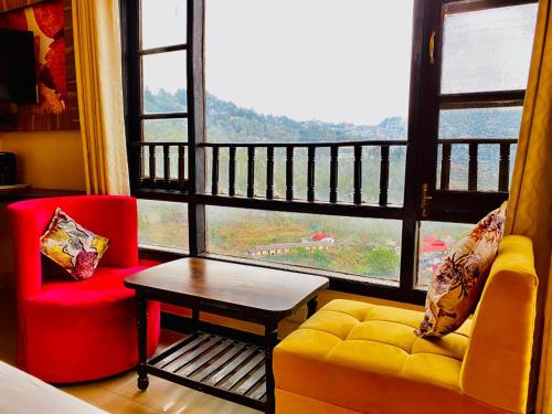西姆拉Aachman velly view with terrace的带沙发和桌子的客厅以及大窗户。