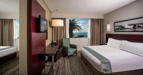 伊丽莎白港Garden Court Kings Beach的配有一张床、一张书桌和一扇窗户的酒店客房