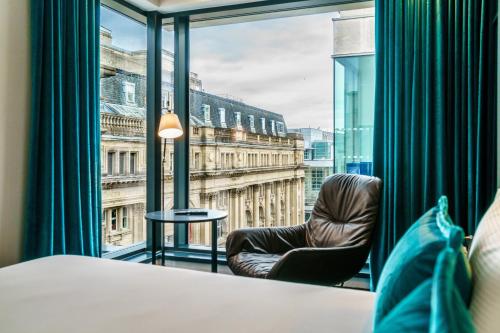 曼彻斯特曼彻斯特皇家交易所墨泰旺酒店的客房设有椅子和大窗户。