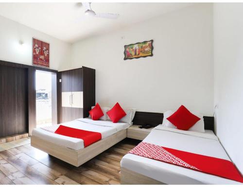 MādhavpurHOTEL MADHUVAN, Madhavpur的宿舍间内的两张床,配有红色枕头
