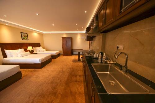 康提Serene Kandy的酒店客房设有两张床和一个带水槽的厨房