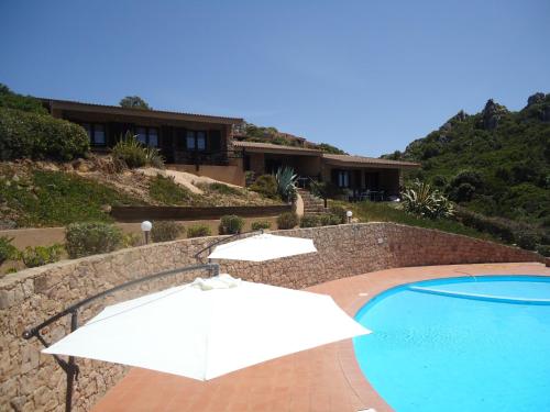 帕拉迪索海岸Villini Cala del Sole - INFINITYHOLIDAYS的一个带遮阳伞和房子的游泳池
