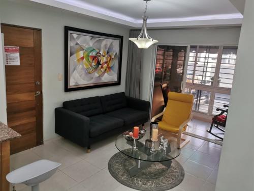 圣多明各Altos de Alemeda, Santo Domingo Oeste的客厅配有黑色沙发和玻璃桌
