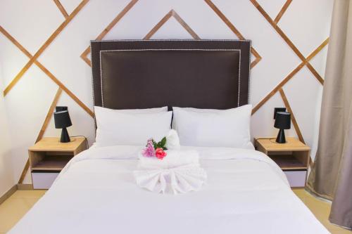 温特和克Deluxe Residence - Windhoek的一张白色的床,上面有黑色床头板和鲜花