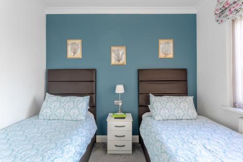埃奇韦尔Room in Guest room - Apple House Wembley Twin Room的卧室设有两张床铺和蓝色的墙壁