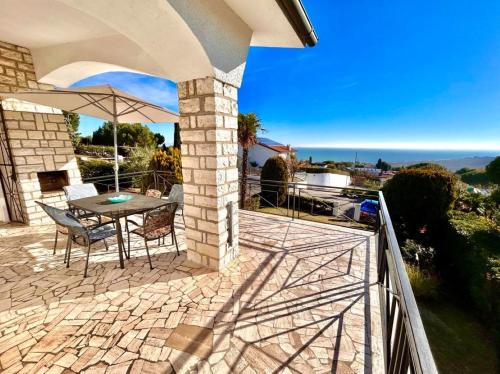 努马纳Villa Edith - stupenda villa con terrazzo vista mare, giardino e spiaggia inclusa的一个带桌子和遮阳伞的庭院