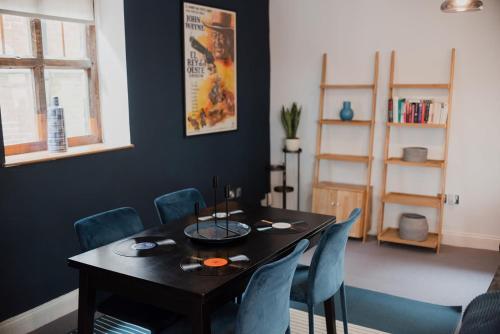 诺里奇Grade II Listed Flint Cottage Sleeps 4的一间用餐室,配有黑桌和蓝色的椅子