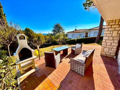 努马纳Villa Renata, bellissima villa con terrazzo vista mare, giardino e spiaggia inclusa的庭院配有桌椅和壁炉。