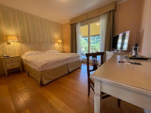 坎诺比奥Villa Palmira Kinderfreies Hotel的一间卧室配有一张床、一张桌子和一台电视