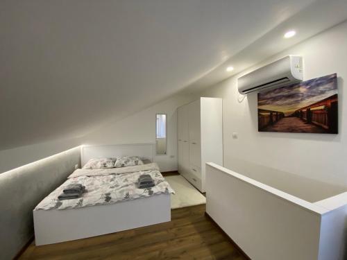 VeternikApartman Marsalforn的白色卧室配有一张床,墙上挂着一幅画