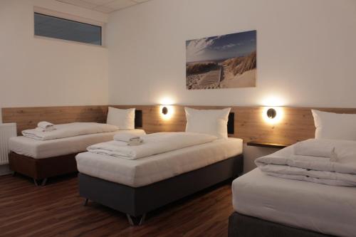 汉诺威Hive Apartments - direkt an der Hannover Messe的带3张床和白色枕头的客房