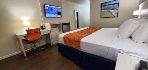 布伦瑞克THE PARAGON of Golden Isles的酒店客房配有一张床、一张书桌和一台电视。