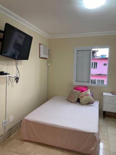 安格拉杜斯雷斯Apto mobiliado, 50 metros da praia.的卧室配有一张床铺,墙上配有电视