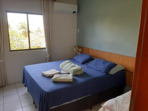 阿奎拉兹CONDOMÍNIO VILA DO MAR的一间卧室配有蓝色的床和毛巾