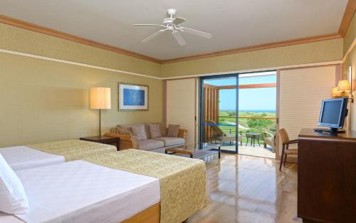 DenizyakaLykia World Links Golf Antalya的一间卧室配有一张床、一张沙发和一台电视