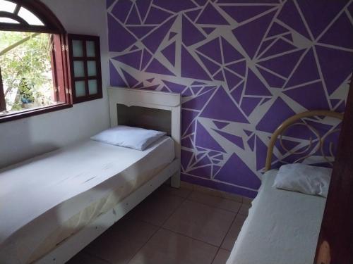 坎普斯戈伊塔卡济斯Guarus house plaza shopping的一间设有两张床和紫色墙壁的客房