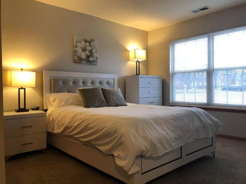 布卢明顿Furnished 3 Bedroom in Bloomington的卧室配有白色床、两盏灯和窗户。