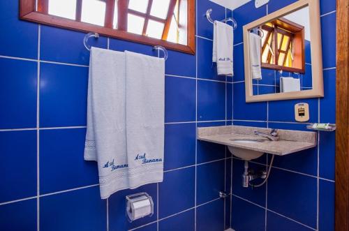 马利西亚斯Pousada Azul Banana - Maresias的蓝色瓷砖浴室设有水槽和镜子