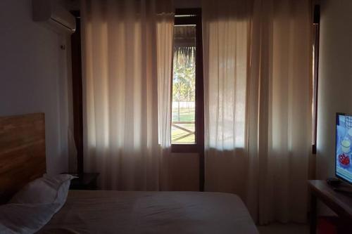 弗雷谢拉斯Flecheiras Eco Residence Un302的一间卧室配有床和带窗帘的窗户