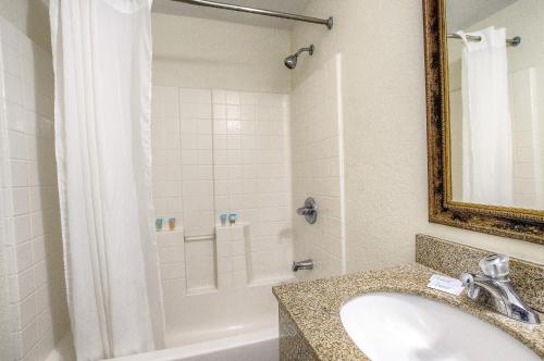代托纳海滩La Bella Oceanfront Inn - Daytona的浴室配有水槽、淋浴和浴缸。