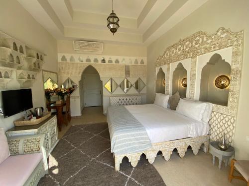 马拉喀什La Villa Des Golfs & PinkCactus的一间带大床和电视的卧室