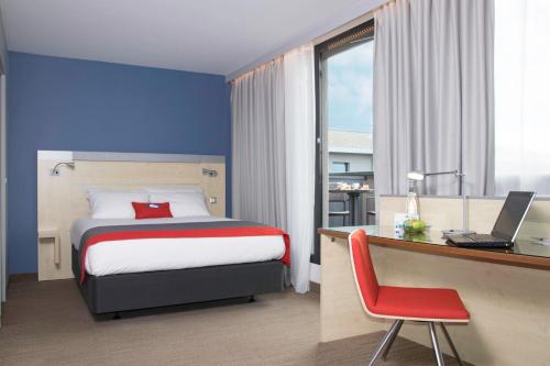 布拉尼亚克快捷假日图卢兹机场酒店的一间卧室配有一张床和一张带笔记本电脑的书桌