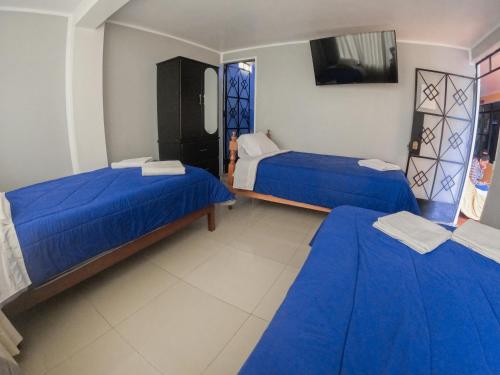 奥克萨潘帕Hospedaje Piura的配有蓝色床单的客房内的两张床