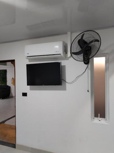 SaravenaHotel Ariza Real的配有电视和壁挂风扇的客房