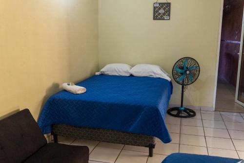 圣安娜Villa La Casita的一间卧室配有一张带蓝色床单的床和风扇