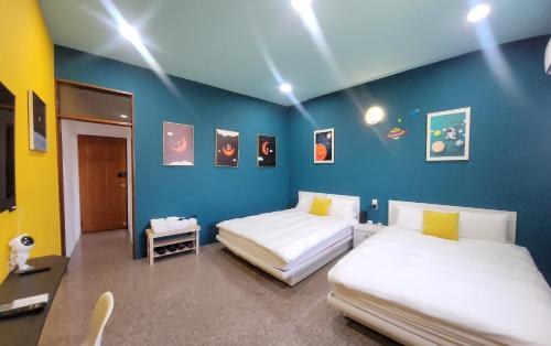 竹山布拉诺主题民宿的配有两张床铺的蓝色墙壁和灯