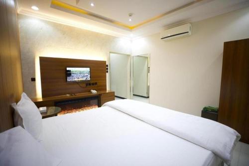 利雅德علم الفريدة للوحدات السكنية المفروشة Alam Faridah Hotel的卧室配有白色的床和墙上的电视。