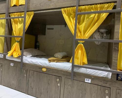 孟买Neenava Dormitory Asalpha的客房内的双层床,配有黄色窗帘