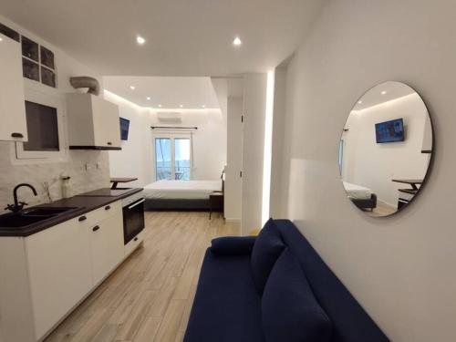 雅典Minimal Athens Apartment的厨房以及带蓝色沙发和镜子的客厅