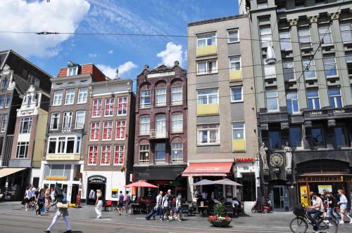 阿姆斯特丹Dam Hotel的一群人走在城市街道上,街道上有很多建筑